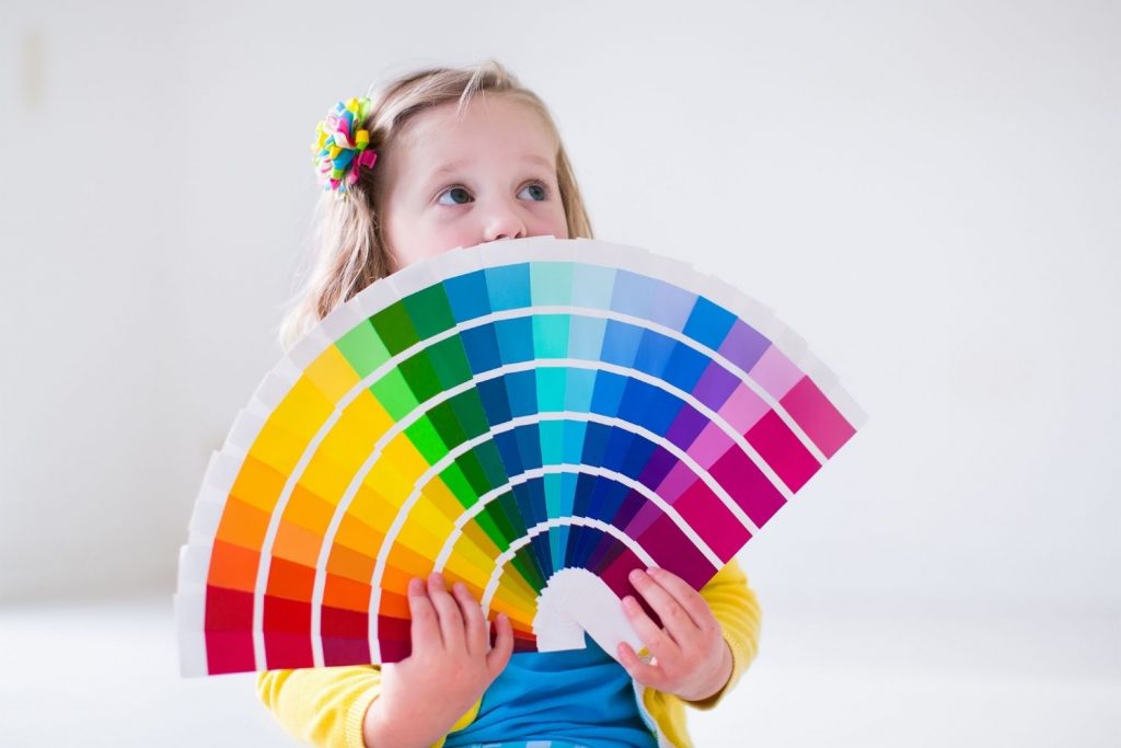 little girl choosing a paint color for the wall