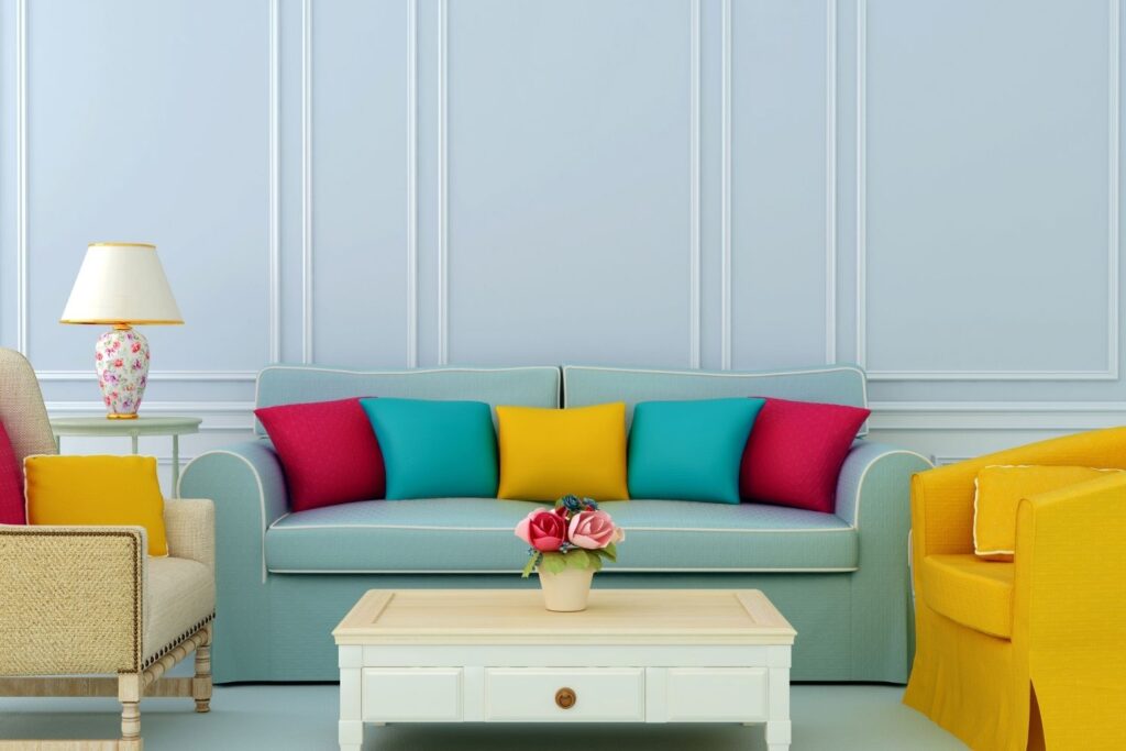 living room with blue walls, two chairs, and a sofa with colorful pillows